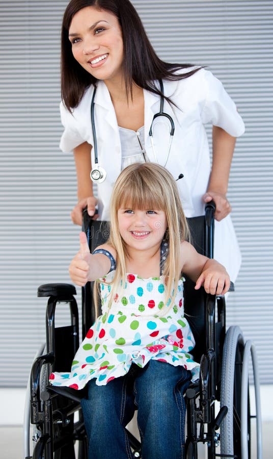 Petite fille de sourire s'asseyant sur le fauteuil roulant photographie stock Petite fille de sourire s'asseyant sur le fauteuil roulant photographie stock