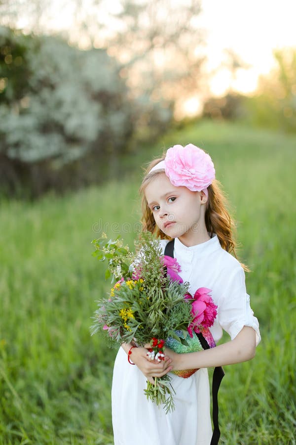Petite fille debout avec bouquet de fleurs et portant une robe blanche. images libres de droits