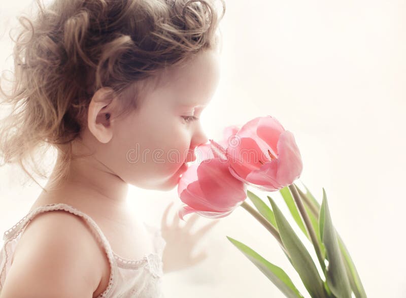 Petite fille douce avec les tulipes roses contre la lumière du soleil de matin. photographie stock libre de droits Petite fille douce avec les tulipes roses contre la lumière du soleil de matin. photographie stock libre de droits