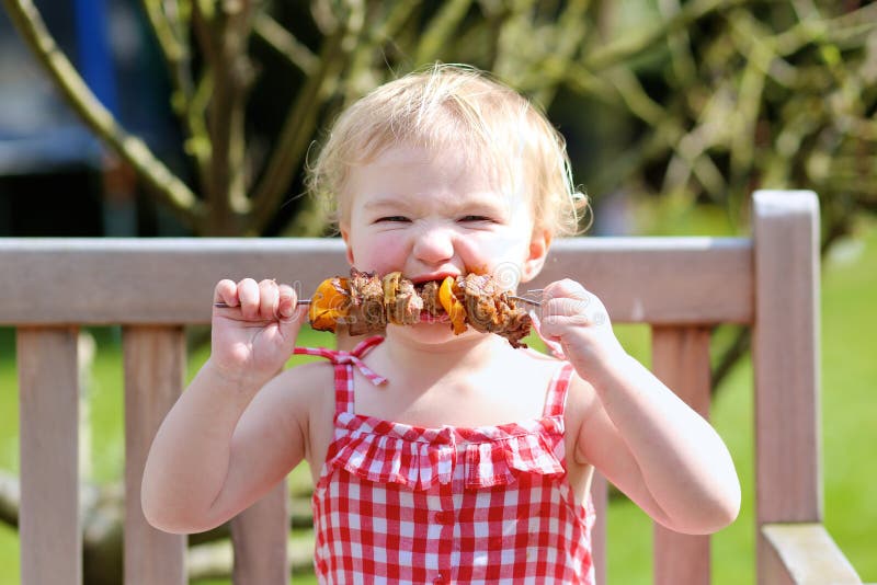Petite fille drôle mangeant de la viande grillée de la cuillère photo libre de droits