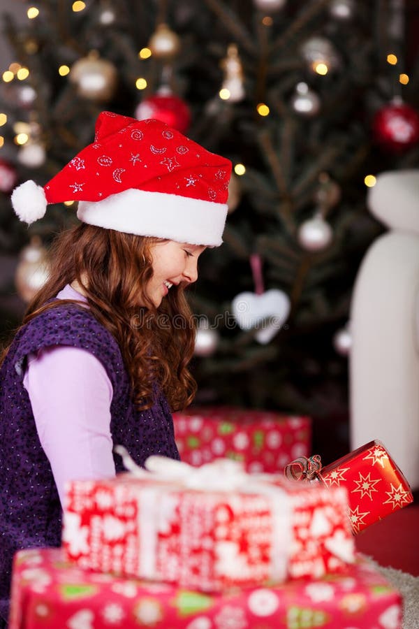 Petite fille déroulant des cadeaux de Noël image libre de droits Petite fille déroulant des cadeaux de Noël image libre de droits