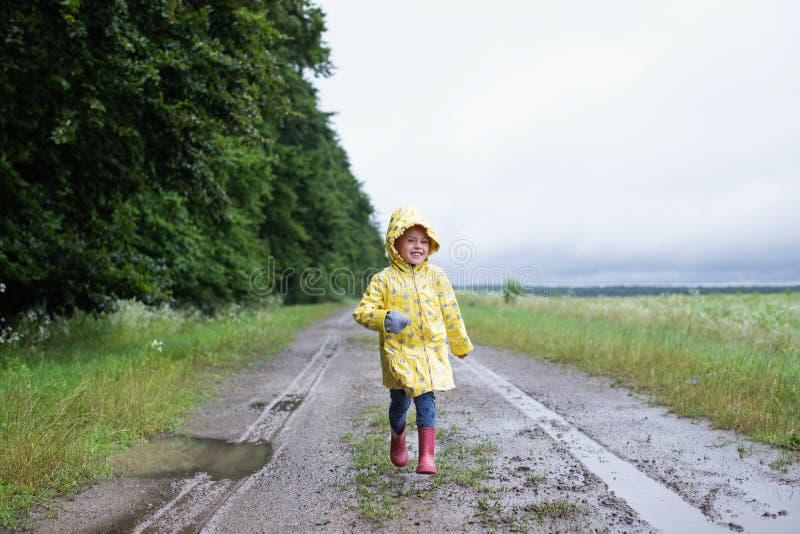 Petite Fille En Imperméable Jaune Court Sur Un Chemin De Terre Avec Des  Boules Et De La Boue Image stock - Image du lifestyle, nature: 244286961