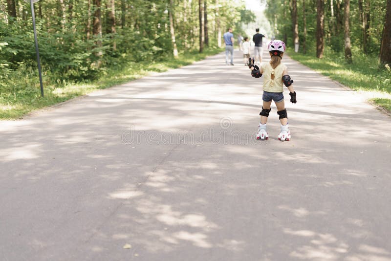Fille Enfant Souriante Dans Un Casque En Rollers De Protection Dans Le Parc