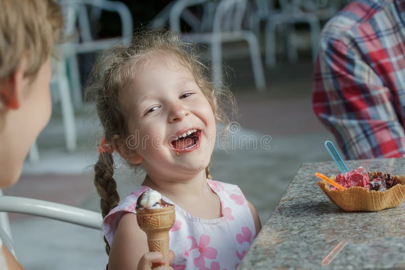 Petite fille et son frère d'enfant de mêmes parents riant pendant la consommation de la crème glacée italienne photographie stock libre de droits