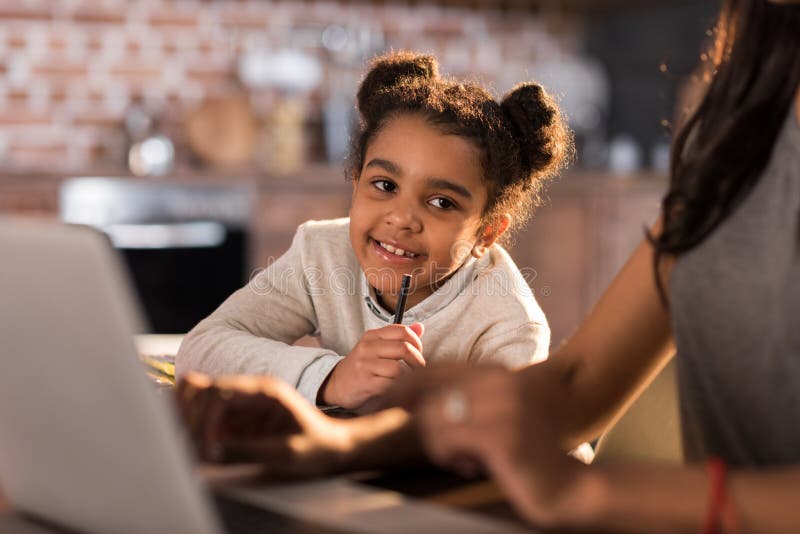 Petite fille faisant le travail avec la mère à l'aide de l'ordinateur portable tout près image libre de droits Petite fille faisant le travail avec la mère à l'aide de l'ordinateur portable tout près image libre de droits