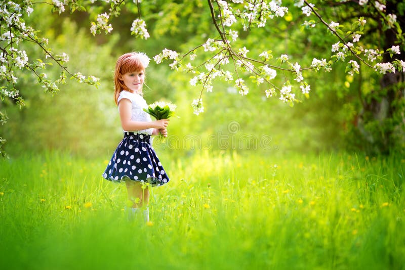 Petite fille heureuse avec un bouquet des lis de la vallée ayant photographie stock libre de droits Petite fille heureuse avec un bouquet des lis de la vallée ayant photographie stock libre de droits