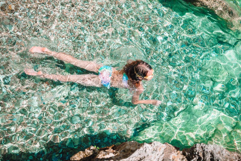 Petite fille heureuse dans l'eau du fond naviguante au schnorchel de piqué de masque avec les poissons tropicaux image libre de droits Petite fille heureuse dans l'eau du fond naviguante au schnorchel de piqué de masque avec les poissons tropicaux image libre de droits