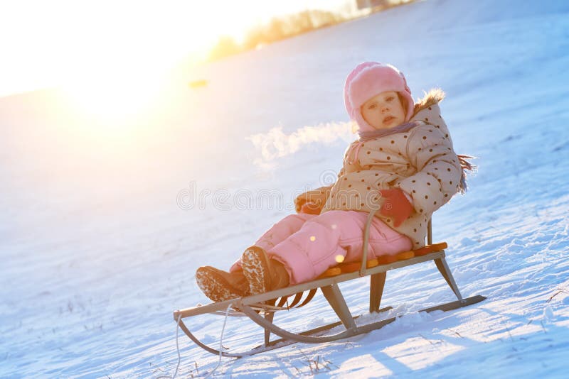 Petite fille heureuse en hiver sur le traîneau photos stock Petite fille heureuse en hiver sur le traîneau photos stock