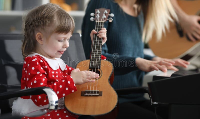 Petite fille heureuse joue ukulele près des parents photo libre de droits