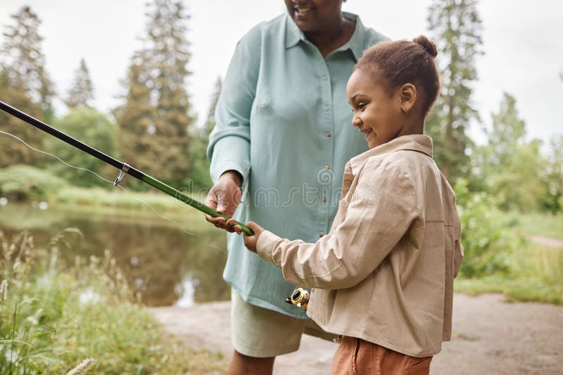 Petite fille heureuse pêche avec parent par rivière dans un beau moment de liaison photographie stock