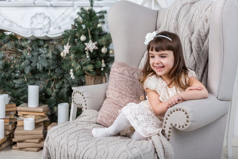 Petite fille heureuse s'asseyant sur le grand fauteuil confortable image libre de droits Petite fille heureuse s'asseyant sur le grand fauteuil confortable image libre de droits