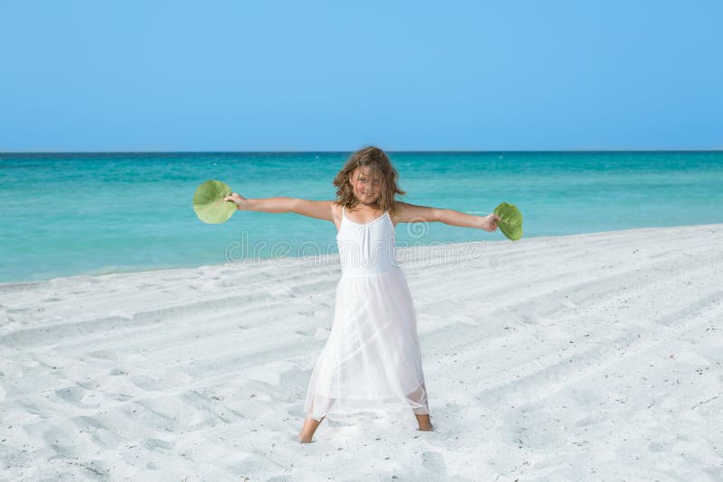 Petite fille heureuse se tenant sur la plage tropicale de sable blanc images libres de droits Petite fille heureuse se tenant sur la plage tropicale de sable blanc images libres de droits