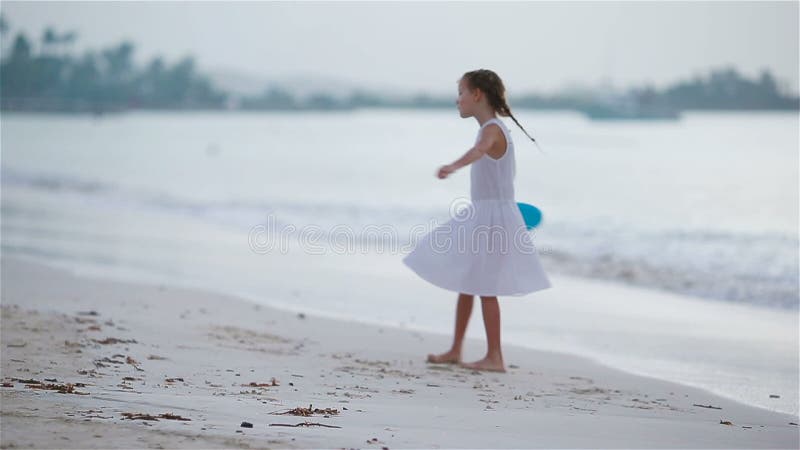 Petite fille jouant avec le disque de vol à la plage au coucher du soleil banque de vidéos