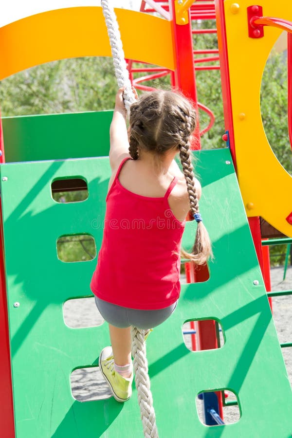 Petite fille jouant sur le terrain de jeu, escaladant le mur sur la corde images stock Petite fille jouant sur le terrain de jeu, escaladant le mur sur la corde images stock