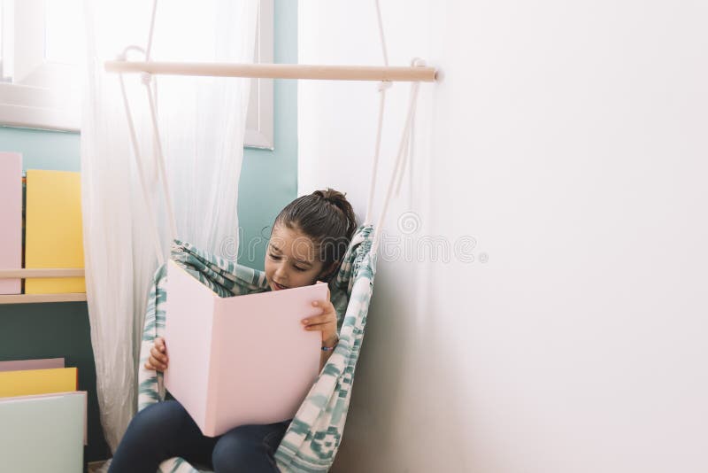 Petite fille lisant ? la maison image libre de droits Petite fille lisant ? la maison image libre de droits