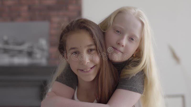 Petite fille mignonne albinos étreignant son amie de brune, amis regardant le sourire de caméra Concept de l'amiti?