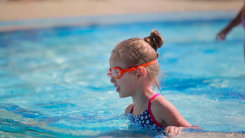 Petite fille mignonne dans les lunettes nageant dans la piscine