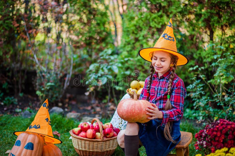 Petite fille mignonne embrasse une citrouille dans le jardin d'automne photographie stock Petite fille mignonne embrasse une citrouille dans le jardin d'automne photographie stock
