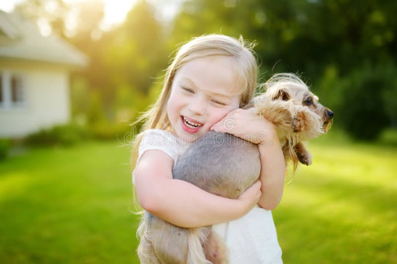 Petite fille mignonne tenant son chien drôle de terrier de Yorkshire image libre de droits Petite fille mignonne tenant son chien drôle de terrier de Yorkshire image libre de droits