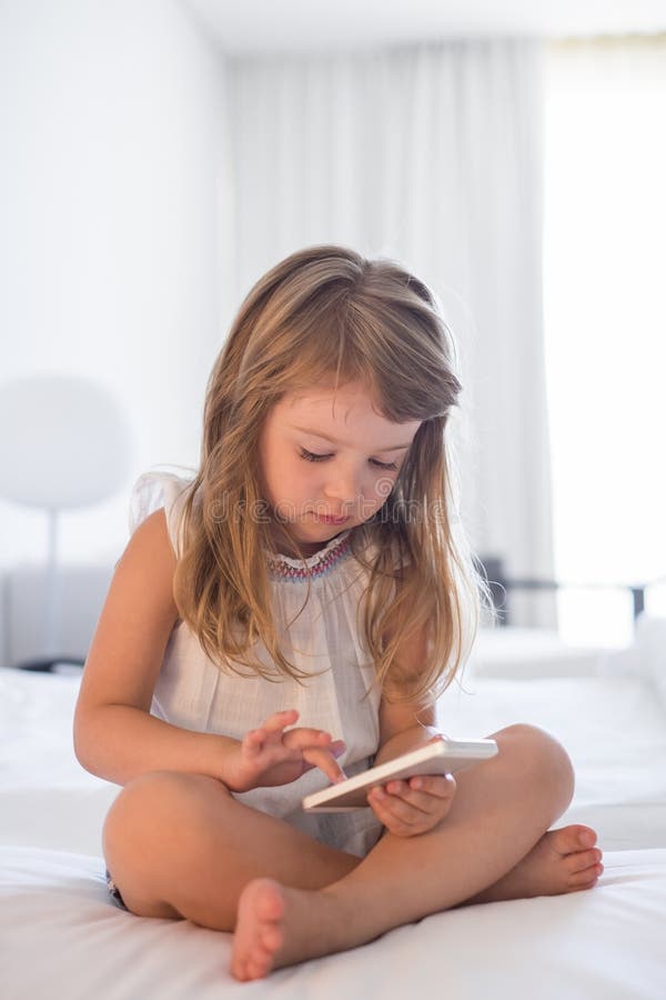 Petite fille mignonne à l'aide du téléphone portable à la maison photo libre de droits Petite fille mignonne à l'aide du téléphone portable à la maison photo libre de droits