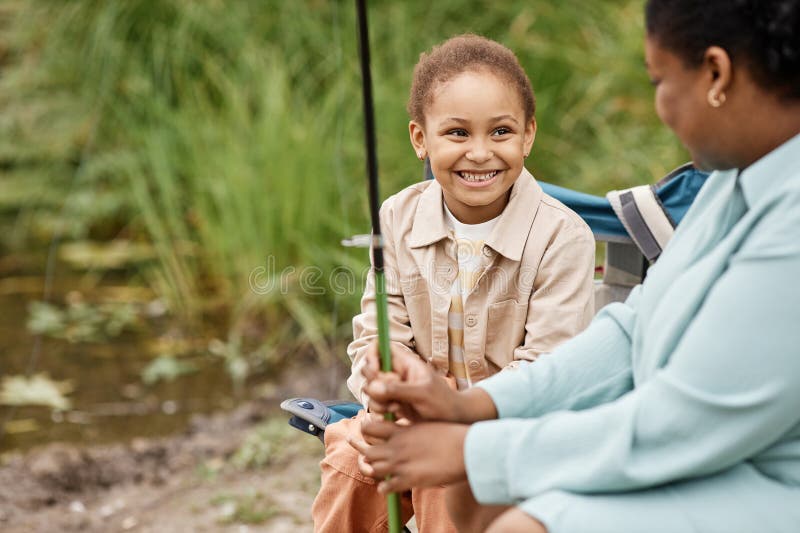 Petite fille noire souriant joyeusement tout en profitant de la pêche avec les parents photos stock