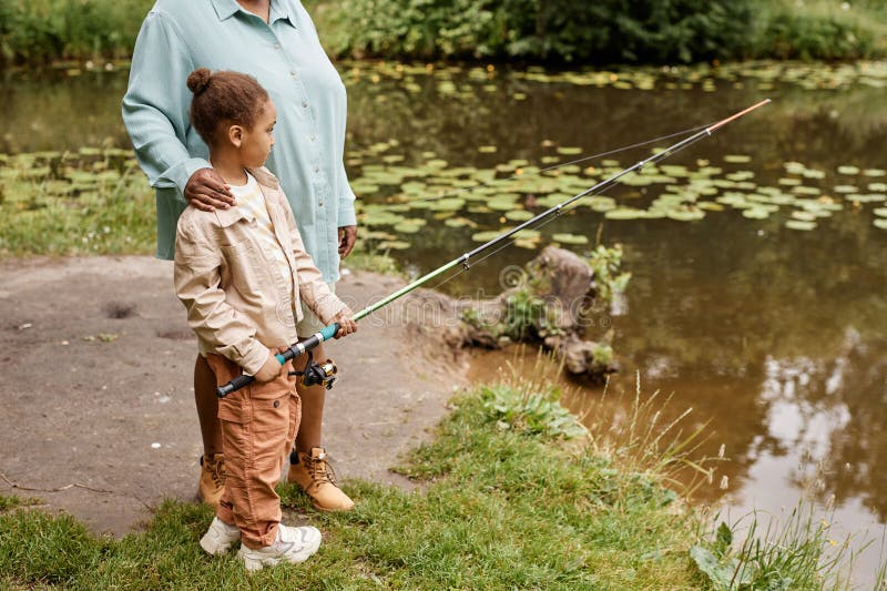 Petite fille noire tenant la canne à pêche et profiter de la mère photos stock