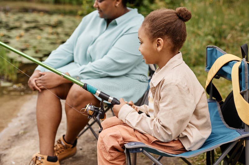 Petite fille noire tenant une canne de pêche tout en profitant du camping en famille images libres de droits