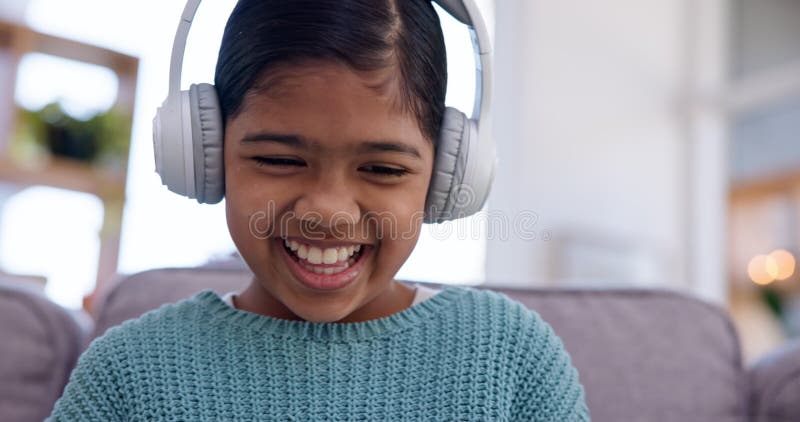 Petite fille ordinateur portable et casque sur canapé rire et regarder une vidéo drôle avec audio-tech dans le salon. écoute des e banque de vidéos