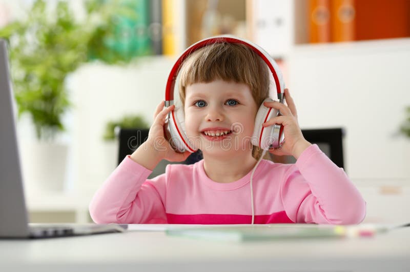 Petite fille portant le casque utiliser l'ordinateur portable image stock