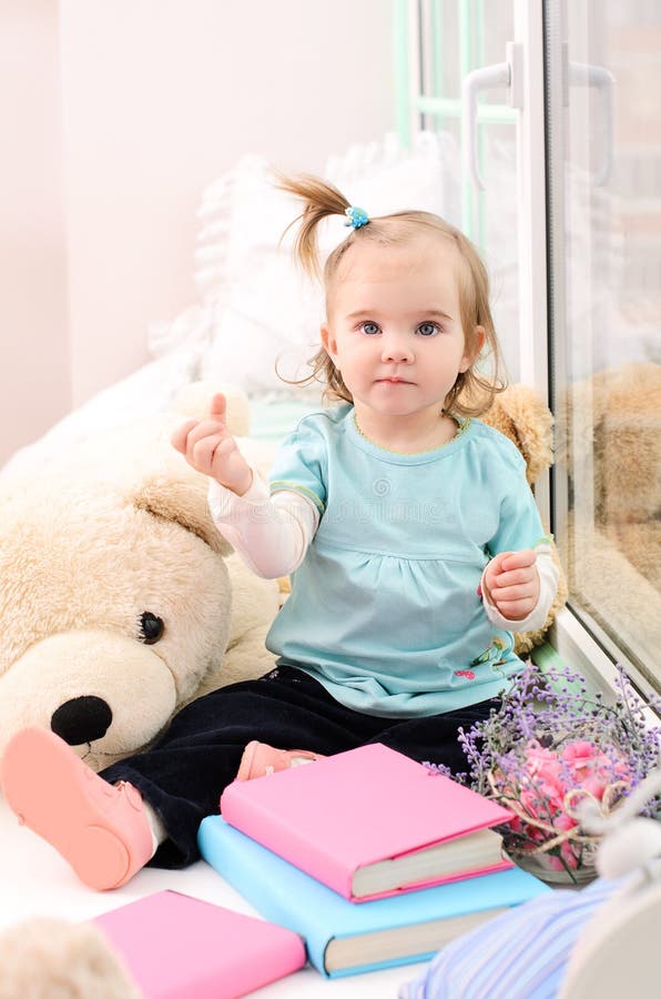 petite fille près de la fenêtre avec des livres photo libre de droits petite fille près de la fenêtre avec des livres photo libre de droits