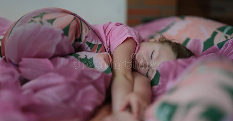 Petite fille qui dort doucement dans son lit photo stock