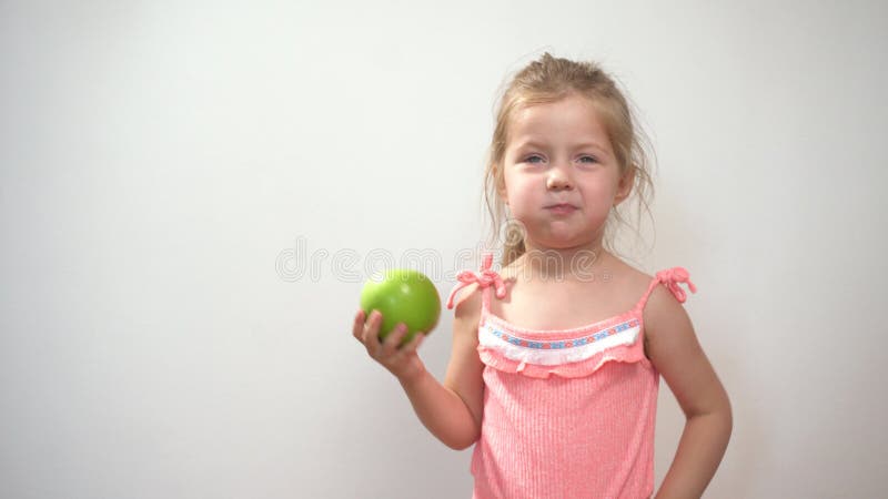 Petite fille qui mange de la pomme aigre fraîche verte au fond blanc