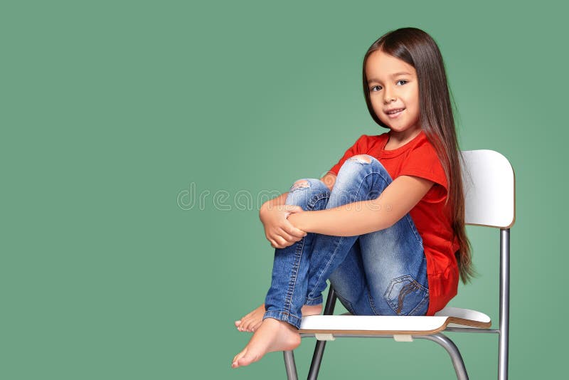 Petite fille s'usant t-court rouge et posant sur la présidence photos stock Petite fille s'usant t-court rouge et posant sur la présidence photos stock