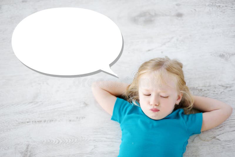 Petite fille se trouvant sur le plancher en bois blanc avec une bulle de la parole au-dessus de sa tête image stock Petite fille se trouvant sur le plancher en bois blanc avec une bulle de la parole au-dessus de sa tête image stock