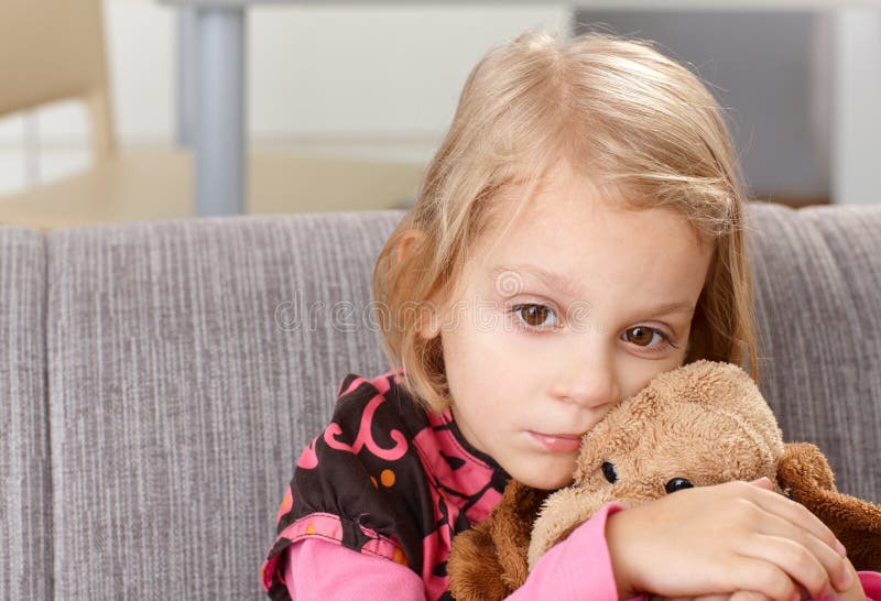 Petite fille seule s'asseyant tristement sur le sofa photos stock Petite fille seule s'asseyant tristement sur le sofa photos stock