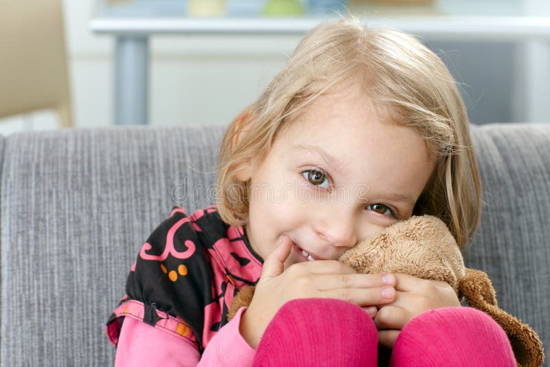 Petite fille souriant espiègle sur le sofa images libres de droits Petite fille souriant espiègle sur le sofa images libres de droits