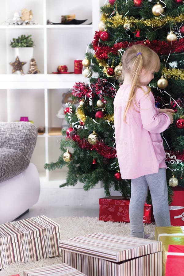 Petite fille à la maison décorant l'arbre de Noël photos stock Petite fille à la maison décorant l'arbre de Noël photos stock