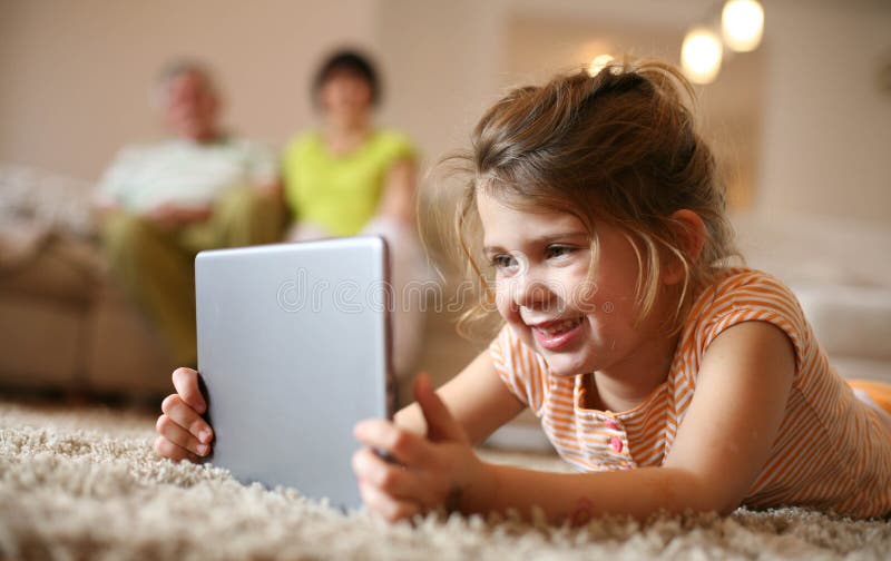 Petite fille à la maison utilisant le comprimé numérique images stock Petite fille à la maison utilisant le comprimé numérique images stock