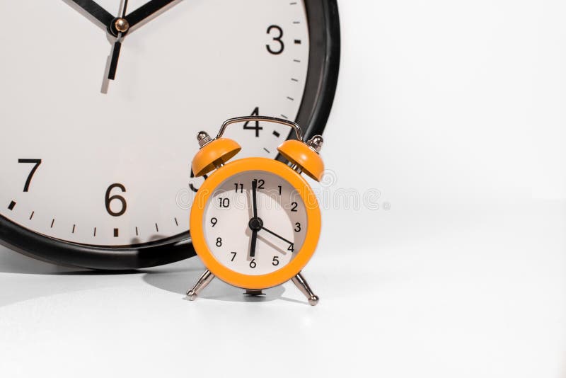 Small orange analog clock with big clock concept time passing faster on white background. Small orange analog clock with big clock concept time passing faster on white background