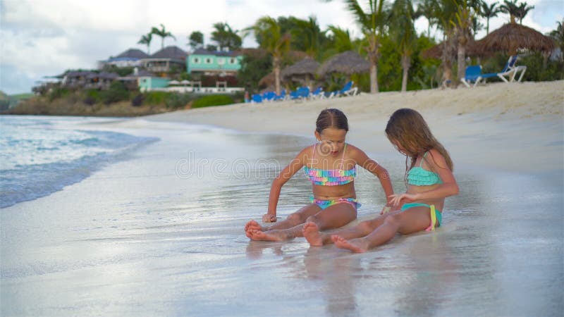 Petites filles adorables jouant avec le sable sur la plage Enfants s'asseyant en eau peu profonde et faisant un château de sable clips vidéos