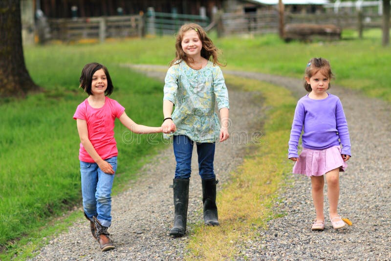 Three little country girls walking on a tractor road. Three little country girls walking on a tractor road.