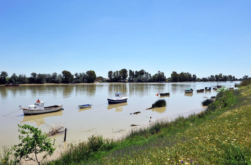 Petits bateaux sur la rivière du Guadalquivir comme elle traverse le del province de Rio, Séville de corions, Andalousie, Espagne photos libres de droits Petits bateaux sur la rivière du Guadalquivir comme elle traverse le del province de Rio, Séville de corions, Andalousie, Espagne photos libres de droits