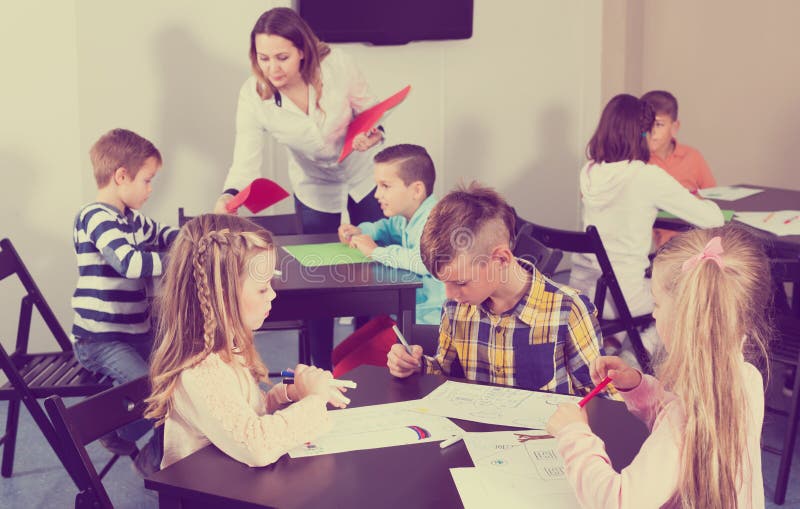 Petits enfants concentrés avec le dessin de professeur dans la salle de classe
