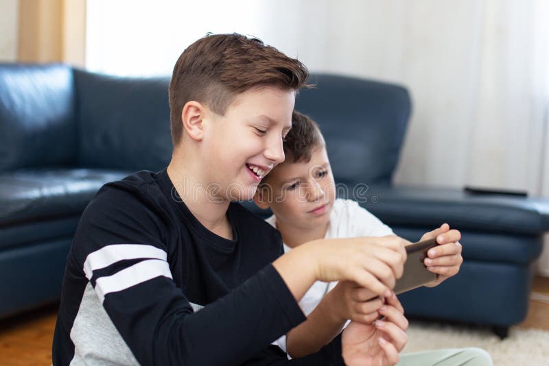 Petits garçons heureux utilisant le smartphone à la maison images stock Petits garçons heureux utilisant le smartphone à la maison images stock