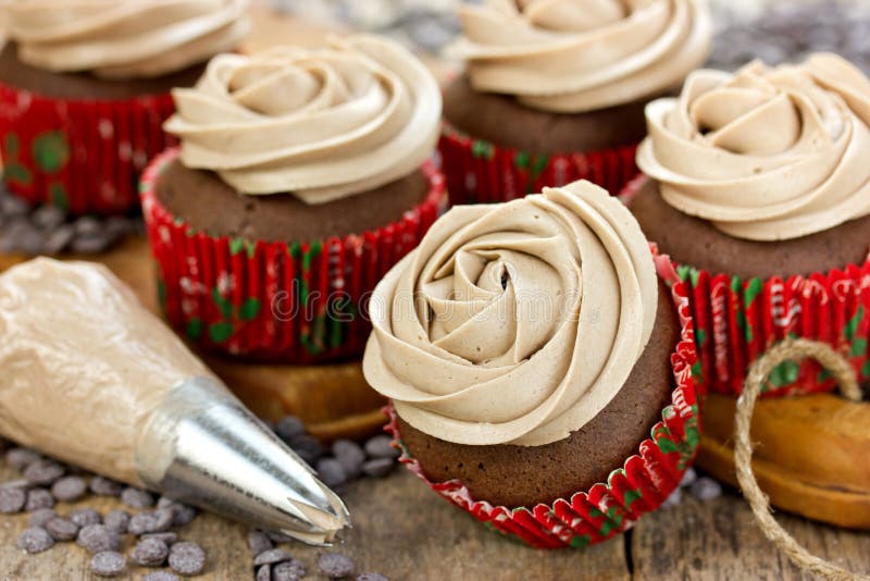 Petits gâteaux de chocolat décorés du glaçage sifflant rose de fin image libre de droits Petits gâteaux de chocolat décorés du glaçage sifflant rose de fin image libre de droits