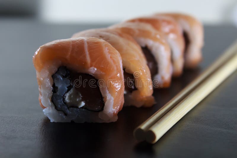 Petits pains de sushi frais délicieux avec le fromage saumoné et fondu du plat noir Nourriture japonaise traditionnelle, concept photos stock Petits pains de sushi frais délicieux avec le fromage saumoné et fondu du plat noir Nourriture japonaise traditionnelle, concept photos stock