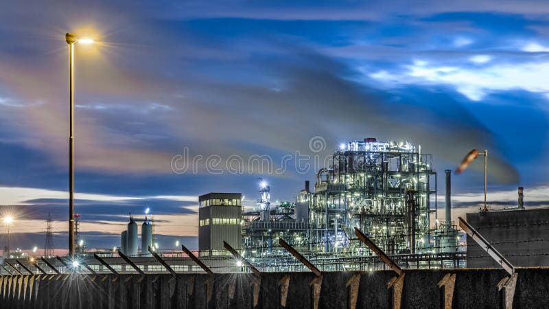 Petrol oil industry in italy at sunset. Beautiful sunset on a industrial site of petrol oil in north Italy under a cloudy blue sky with wind smoke and street stock photography Petrol oil industry in italy at sunset. Beautiful sunset on a industrial site of petrol oil in north Italy under a cloudy blue sky with wind smoke and street stock photography
