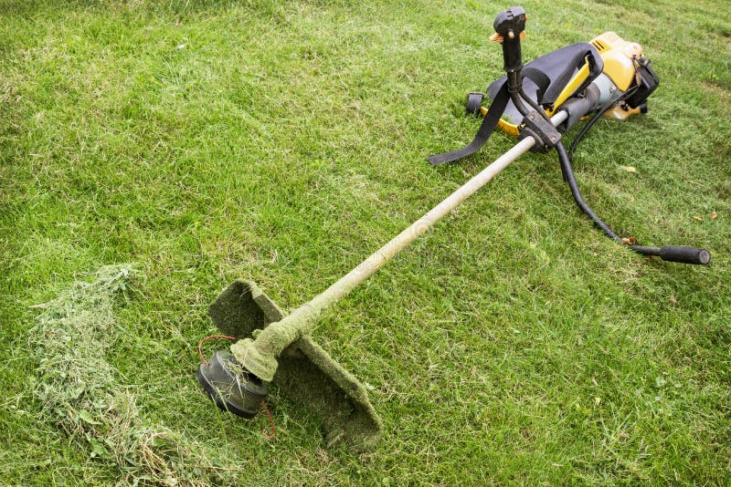 Petrol trimmer is on the sloped lawn