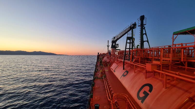 Gas tanker proceeding near the mountainous shore of the island after sunset. Gas tanker proceeding near the mountainous shore of the island after sunset.