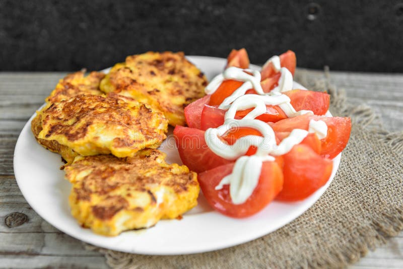 Petti di pollo ricoperti di formaggio, pomodori sul piatto bianco, sulla vecchia tavola di legno fotografia stock Petti di pollo ricoperti di formaggio, pomodori sul piatto bianco, sulla vecchia tavola di legno fotografia stock